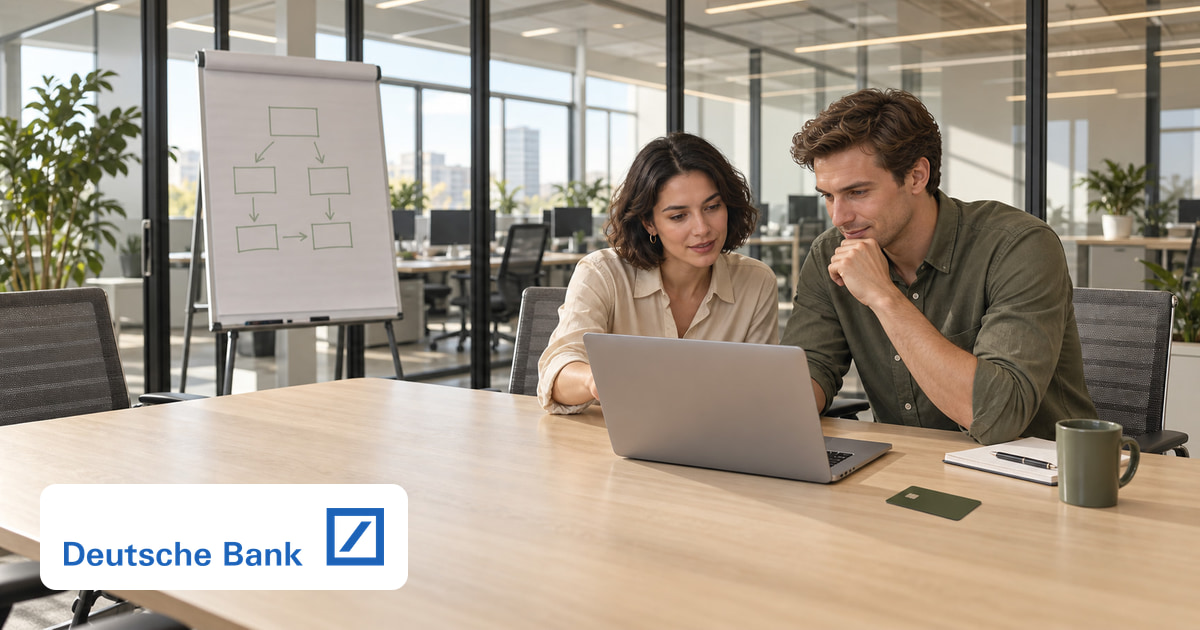 Ein Mann und eine Frau gemeinsam am Laptop im Büro, eine Kreditkarte auf dem Tisch und das Logo von Deutsche Bank unten links.