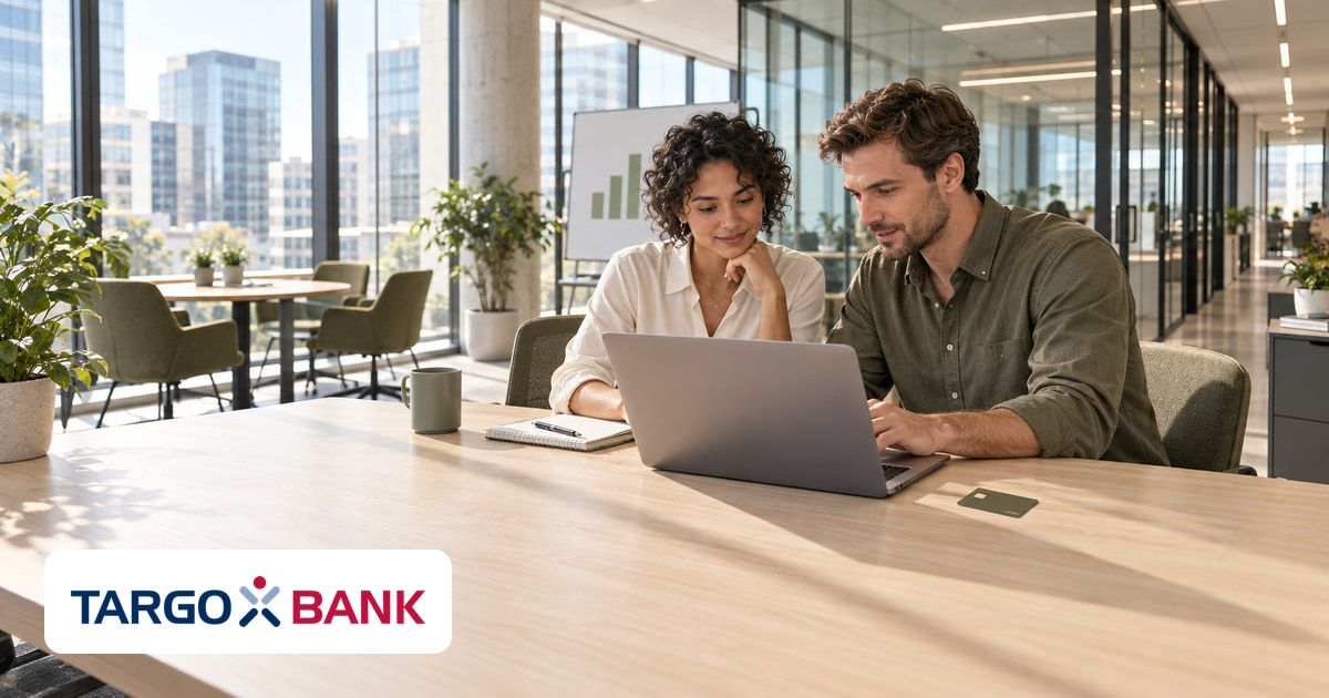 Ein Mann und eine Frau gemeinsam am Laptop im Büro, eine Kreditkarte auf dem Tisch und das Logo von TARGOBANK unten links.